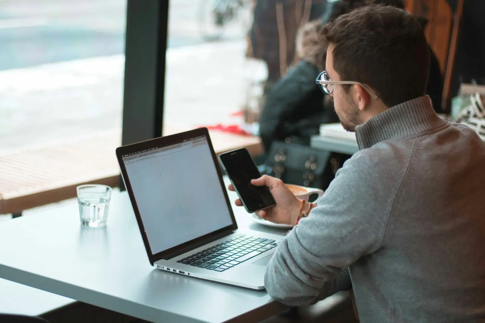 A business owner working on a laptop beside a window