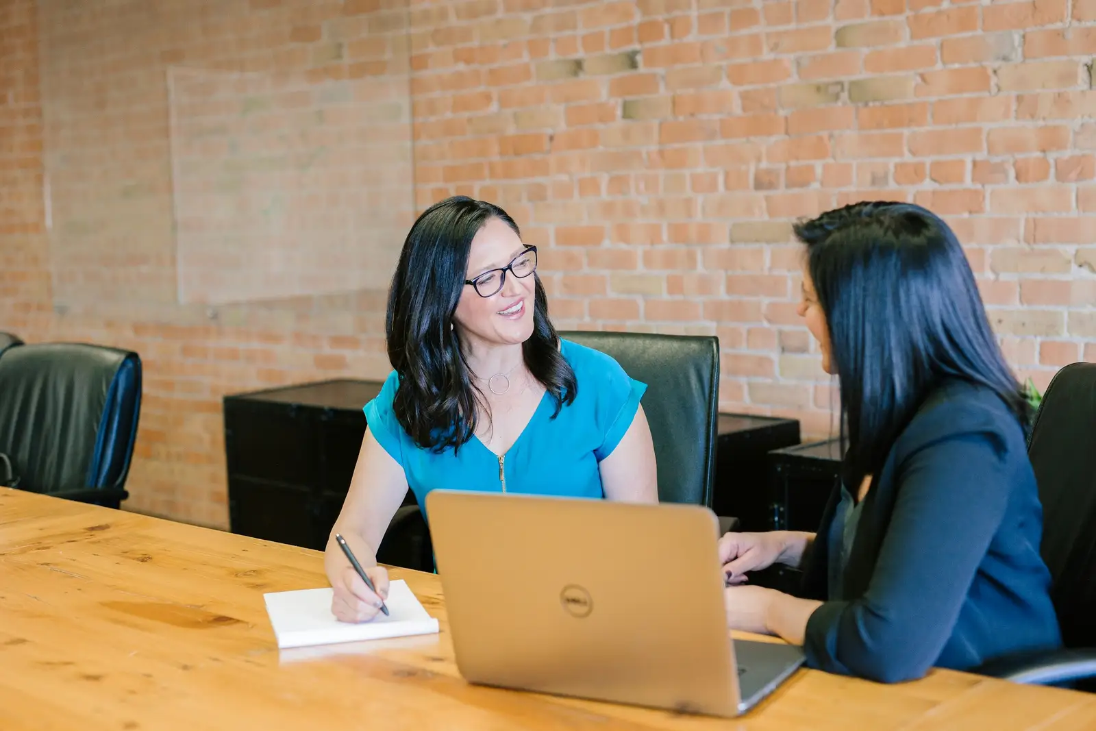 Two people talking through a plan at a table with a laptop
