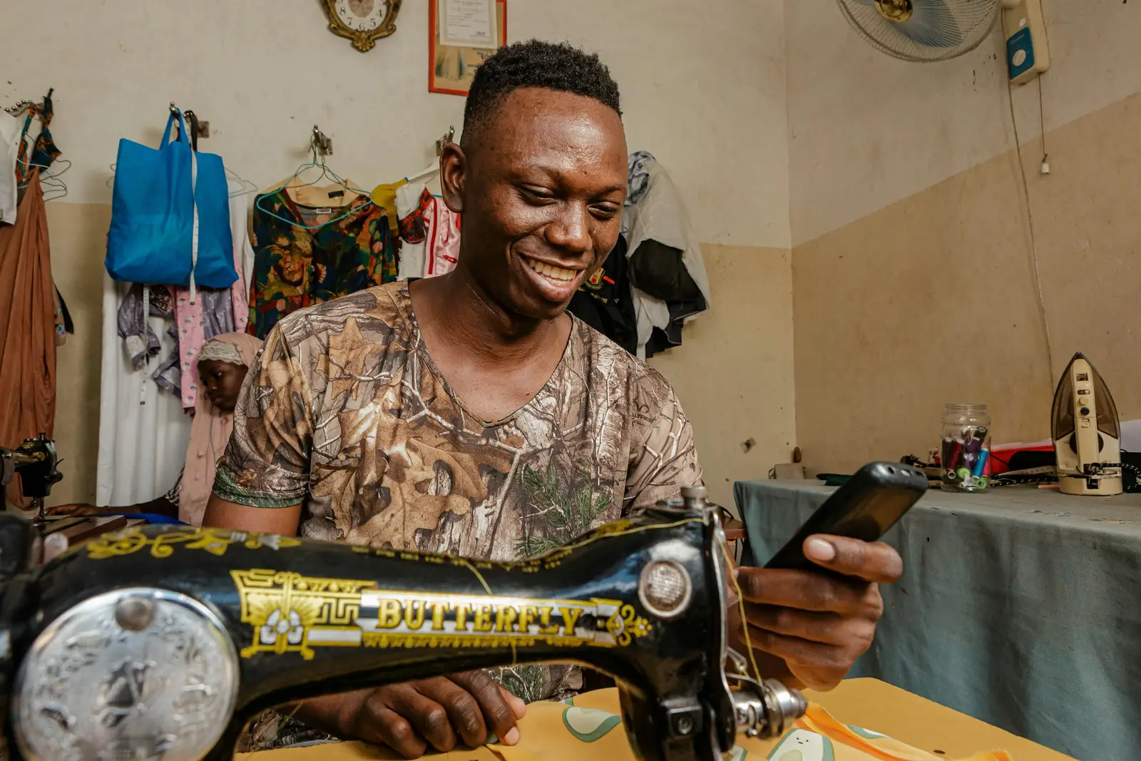A tailor smiling while working at a sewing machine